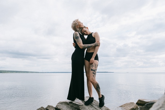 Dve ženy s tetovaním sa objímajú pri jazere 